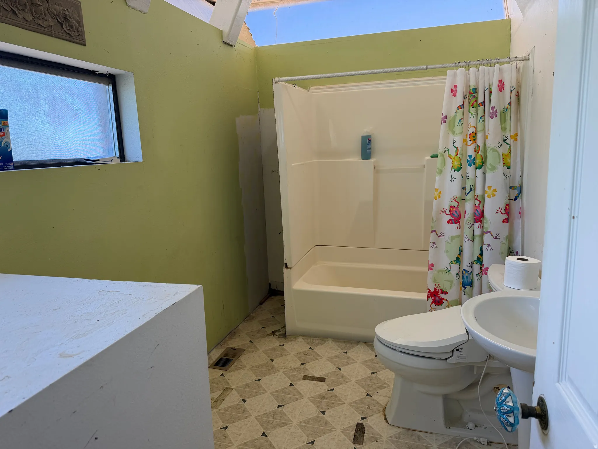 Bathroom featuring a built-in shower/tub combination, pedestal sink, toilet, and patterned floor tiles