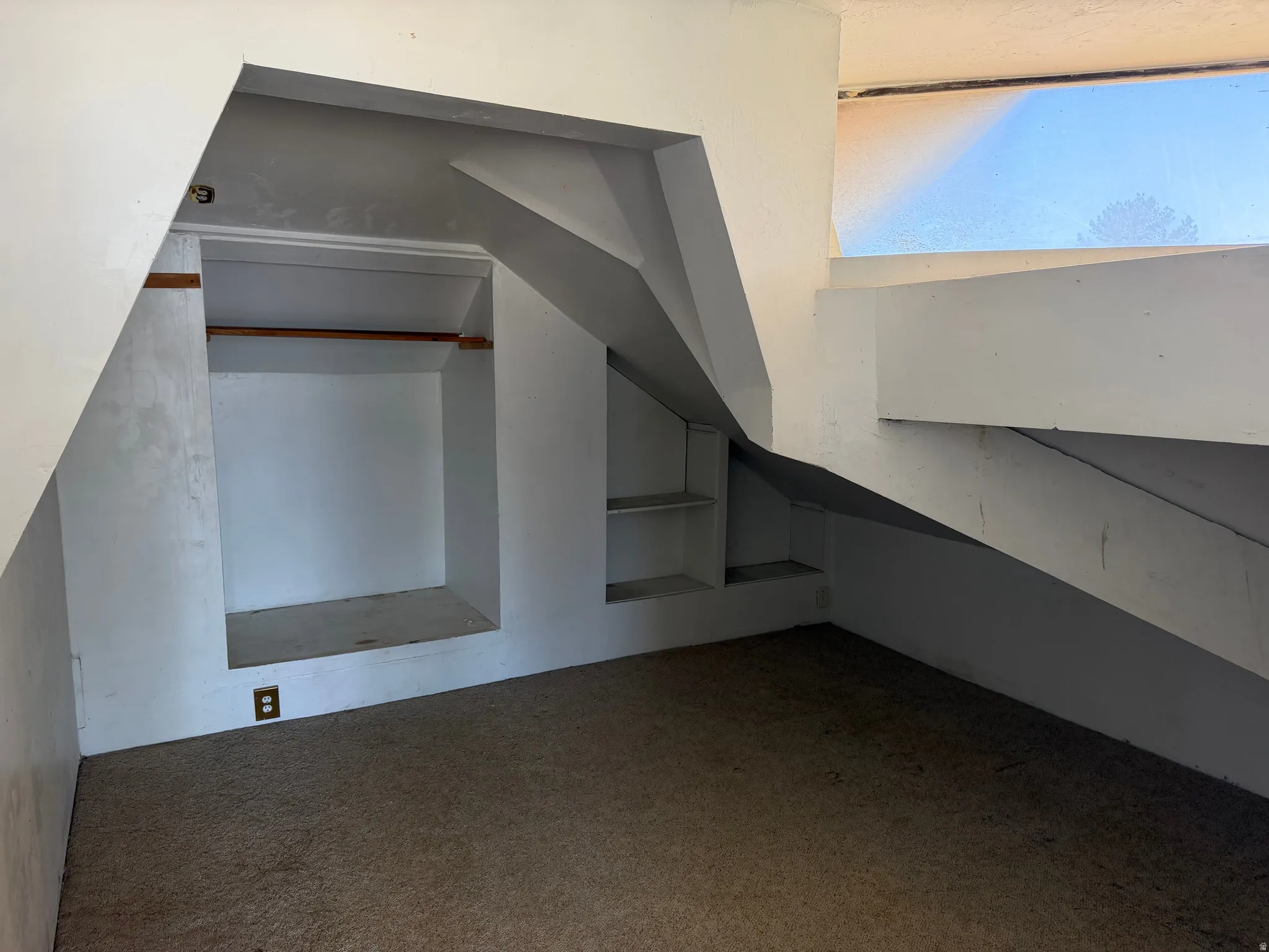Built-in shelving and a clothing rod offer storage options in this carpeted room