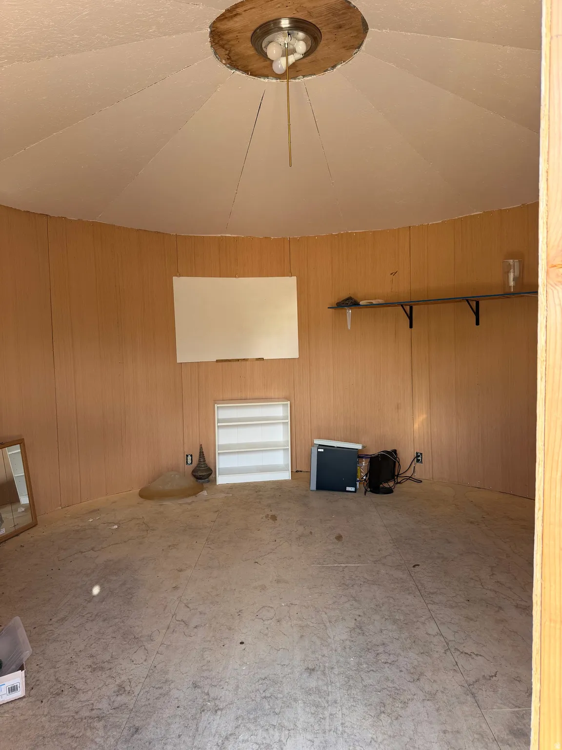 Room featuring light wood-finish wall paneling, a circular ceiling with a central flush-mount light fixture, and light-toned flooring