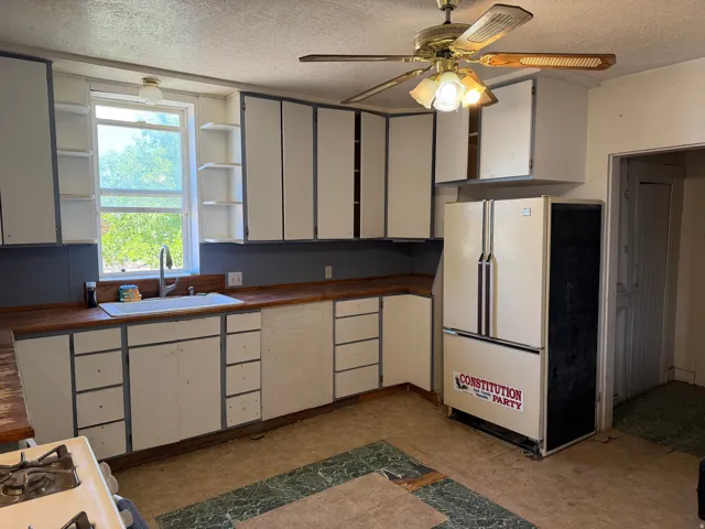 Kitchen featuring wood-finish countertops, white cabinetry with open shelving, and a dual-basin sink with a gooseneck faucet