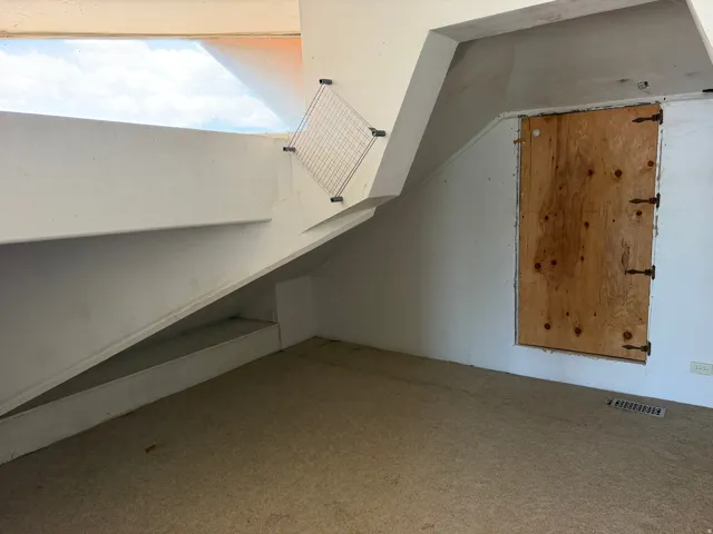Carpeted floor with white walls and a light-filled upper window