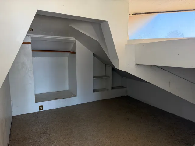 Built-in shelving and a clothing rod offer storage options in this carpeted room