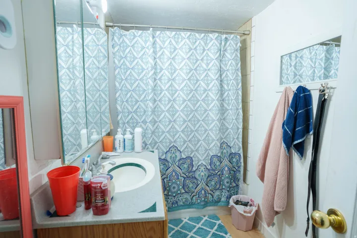 Bathroom vanity with an integrated sink, a mirrored medicine cabinet, and a shower area with tiled walls