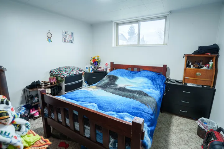 Room featuring a wood-finish bed frame, light-colored walls, and a window with exterior visibility