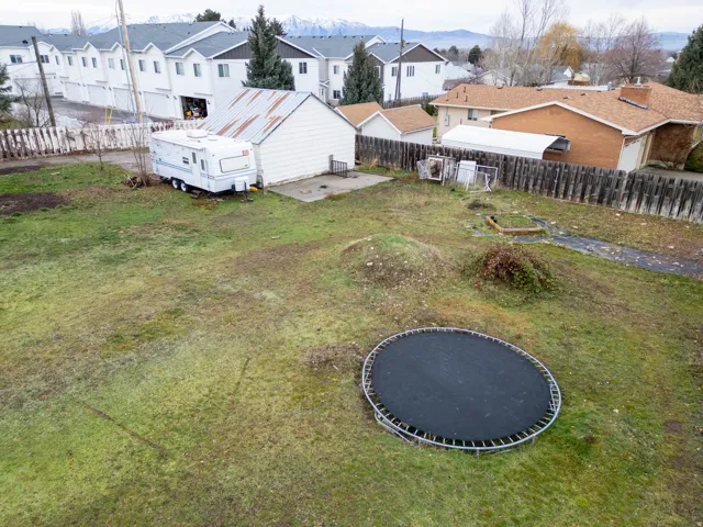 Expansive grassy lot with mature perimeter fencing and mountainous backdrop