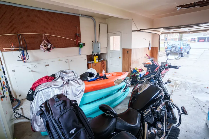 Attached garage with pegboard wall storage, built-in lower cabinetry, and a service door