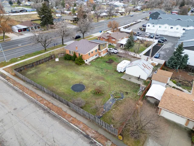 Spacious property with a large grass yard, perimeter fencing, brick exterior, and a visible detached shed structure