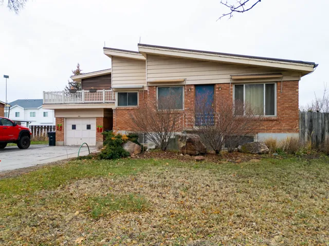Split-level residence featuring brick and horizontal siding, an integrated single-car garage, and an upper-level balcony with white railing