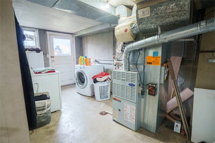 Utility room featuring a Carrier brand furnace and exposed ductwork
