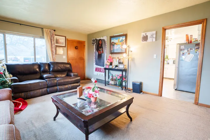 Living area featuring neutral-toned wall paint, carpet flooring, and a large window providing natural light