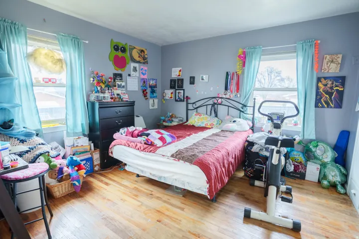 Bedroom featuring wood-finish flooring, two large windows with natural light, and light gray walls