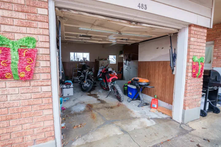 Attached garage with brick exterior featuring a concrete floor, wood-paneling accents, and a window for natural light