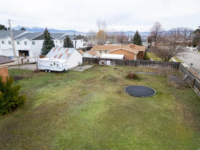 Spacious property featuring a large grassy area, a privacy fence, and distant mountain scenery