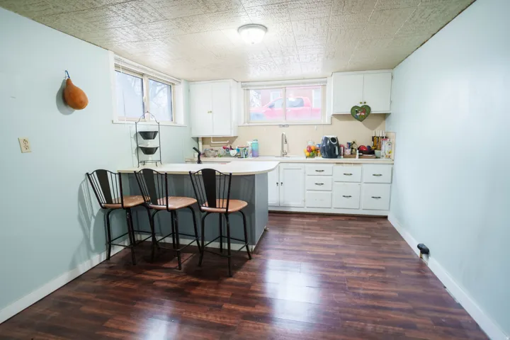 Kitchenette featuring wood-finish flooring, white cabinetry, and a light-colored countertop