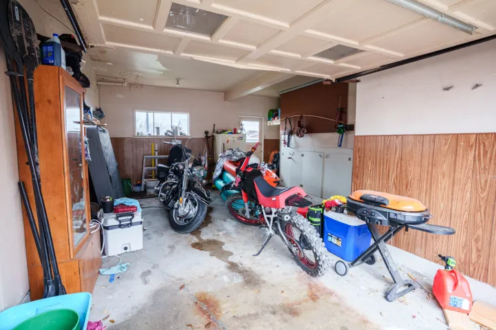 Attached garage featuring concrete flooring, wood-panel wainscoting, built-in cabinetry, upper windows, and a coffered ceiling