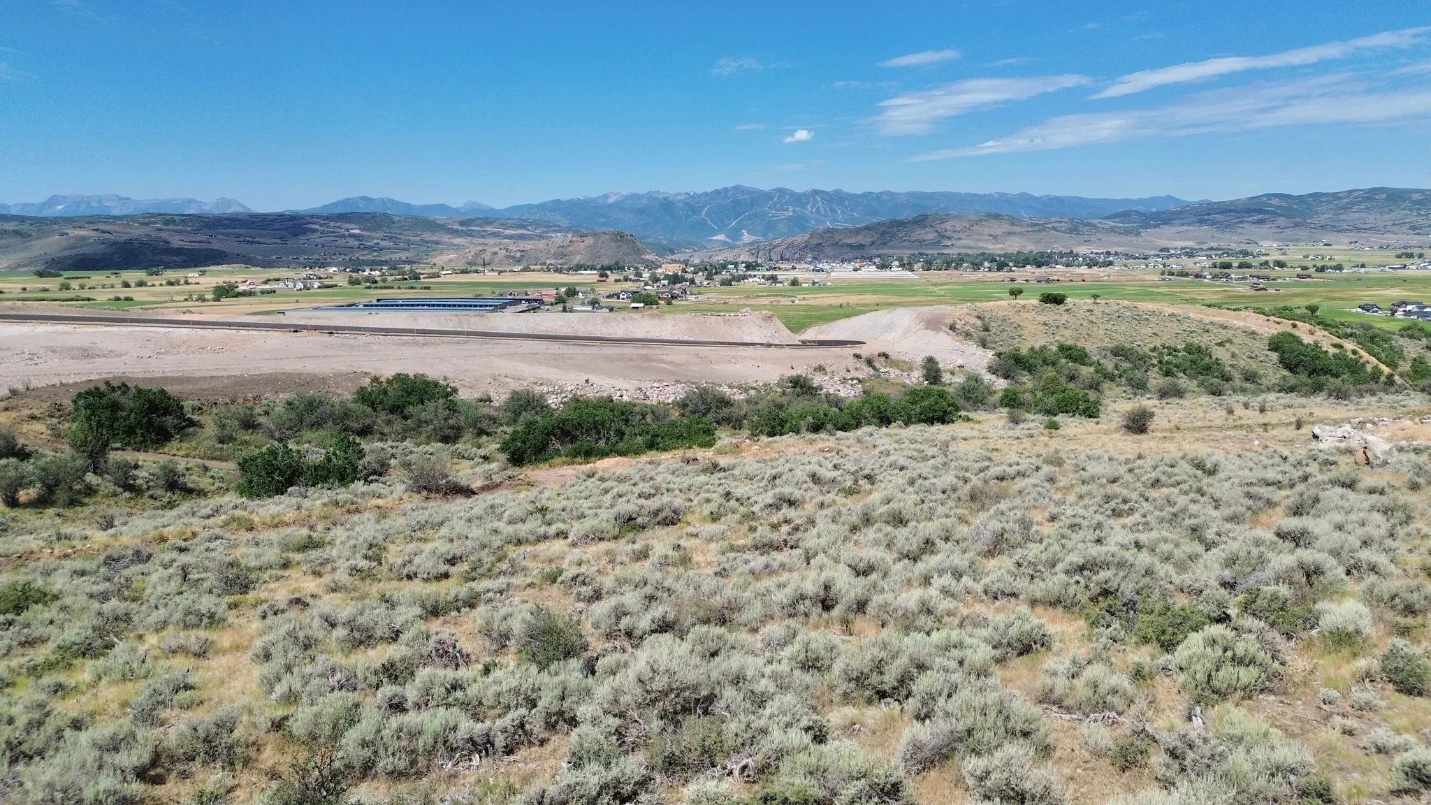 Expansive undeveloped land with natural vegetation and distant mountain ranges under a clear sky