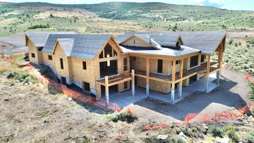 Expansive new construction with multiple gabled rooflines, exposed wood framing, and a tiered concrete patio