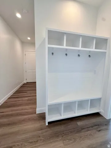 Built-in white storage unit featuring upper cubbies, lower cubbies, and a bench with coat hooks