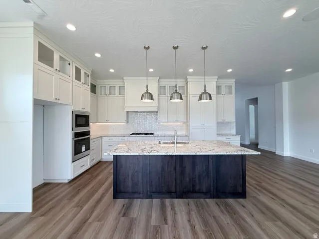 Kitchen featuring a dark wood-finish island with a light-toned countertop, complemented by white cabinetry with glass-front accents