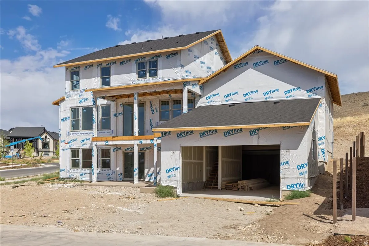 Two-story new construction featuring a covered patio, upper-level balcony, multiple windows, and an integrated garage