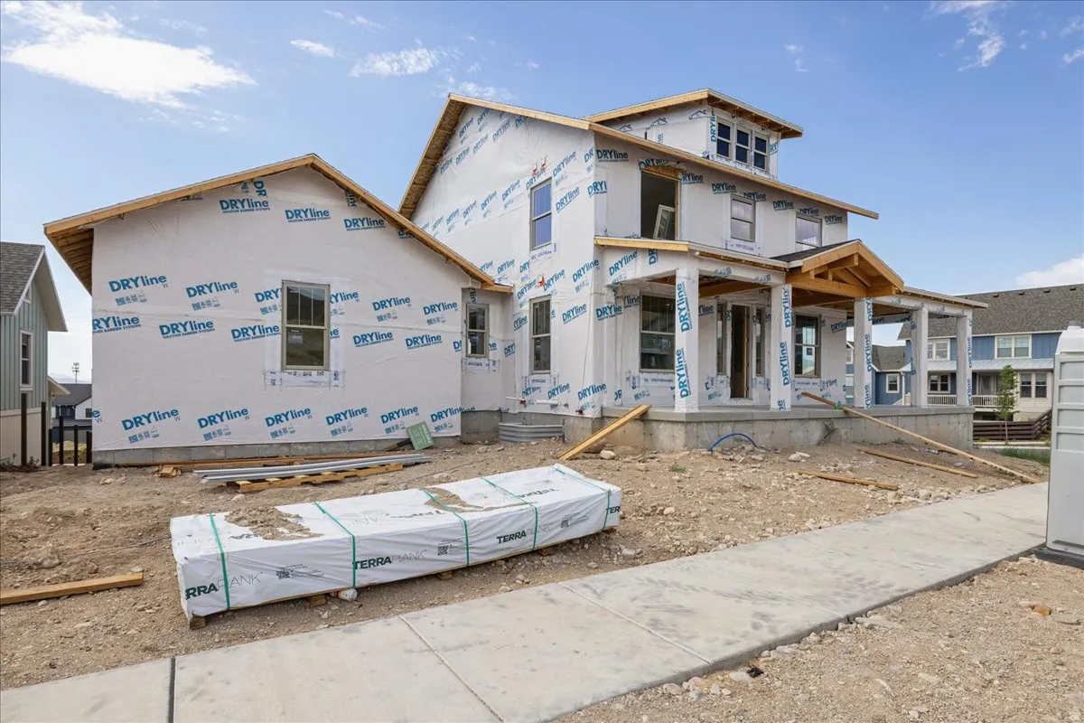 Newly constructed residence featuring a two-story design with an attached single-story section, an elevated covered front porch with exposed beam accents, multiple large windows, and a prominent second-story dormer