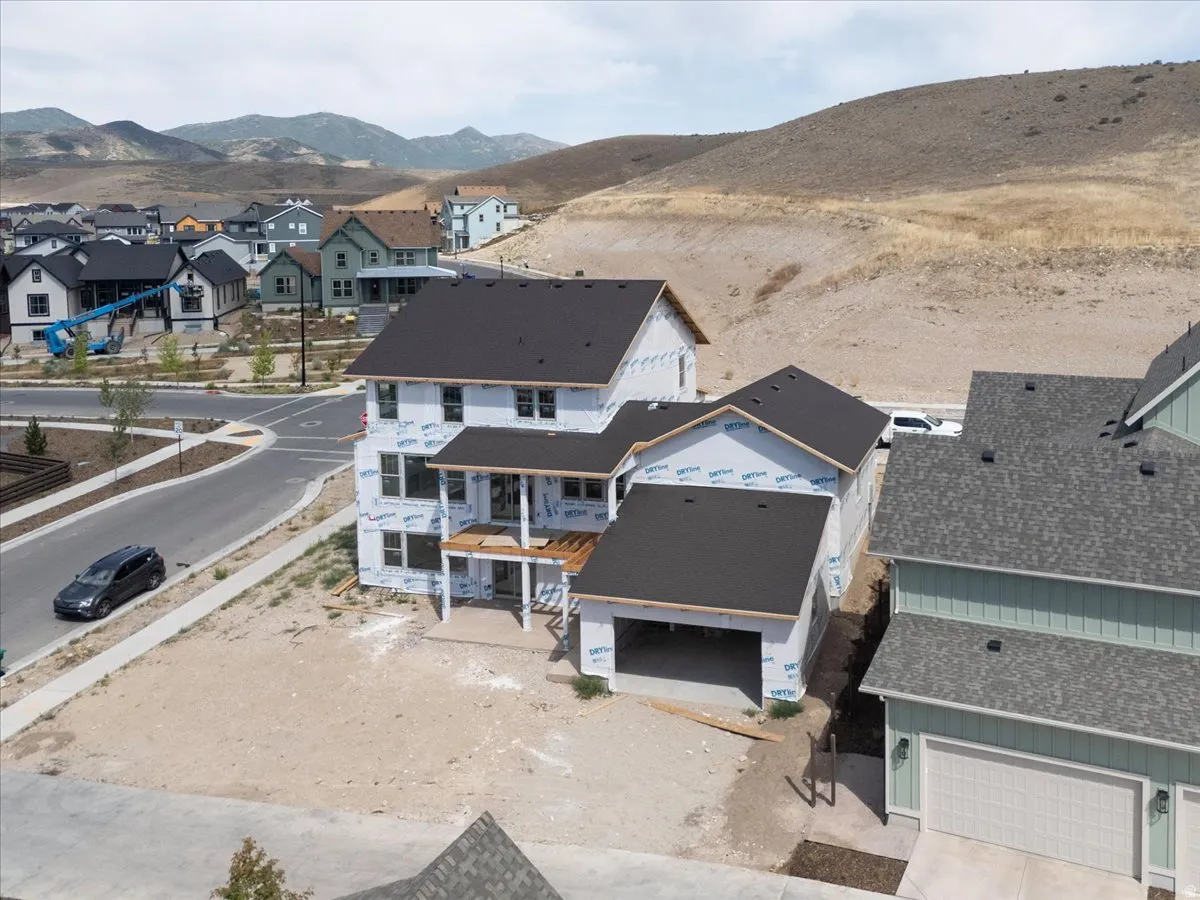 New construction residence featuring an attached garage, covered patio, dark shingle roofing, and a prominent corner lot location