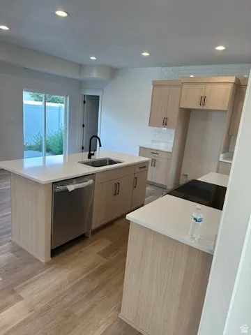 Modern kitchen featuring wood-finish cabinetry, light-toned countertops, and a built-in stainless steel dishwasher