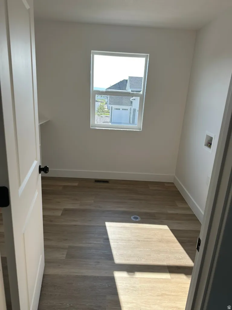 Room featuring wood-finish flooring, a contemporary window, and white painted walls and built in shelf.