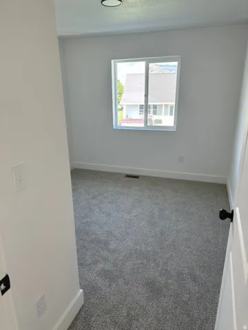 Bedroom featuring a single window, grey carpet, and white walls