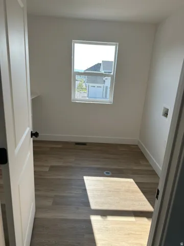 Room featuring wood-finish flooring, a contemporary window, and white painted walls and built in shelf.