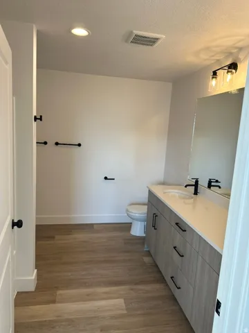 Contemporary bathroom featuring wood-finish flooring, a vanity with a light-toned countertop, a built-in sink, tub/shower combination and matte black fixtures
