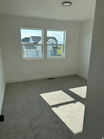 Bright room with dual windows, new gray carpeting, white baseboards, and a contemporary flush-mount ceiling light