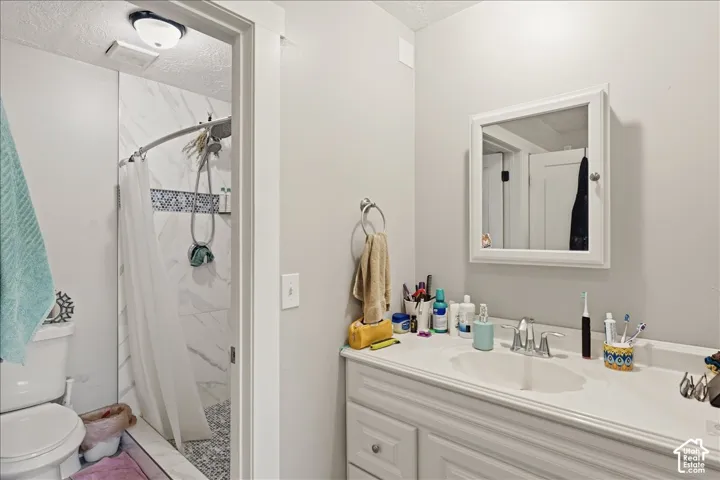 Bathroom featuring a vanity with an integrated sink, built-in medicine cabinet, and a tiled shower with mosaic accent band