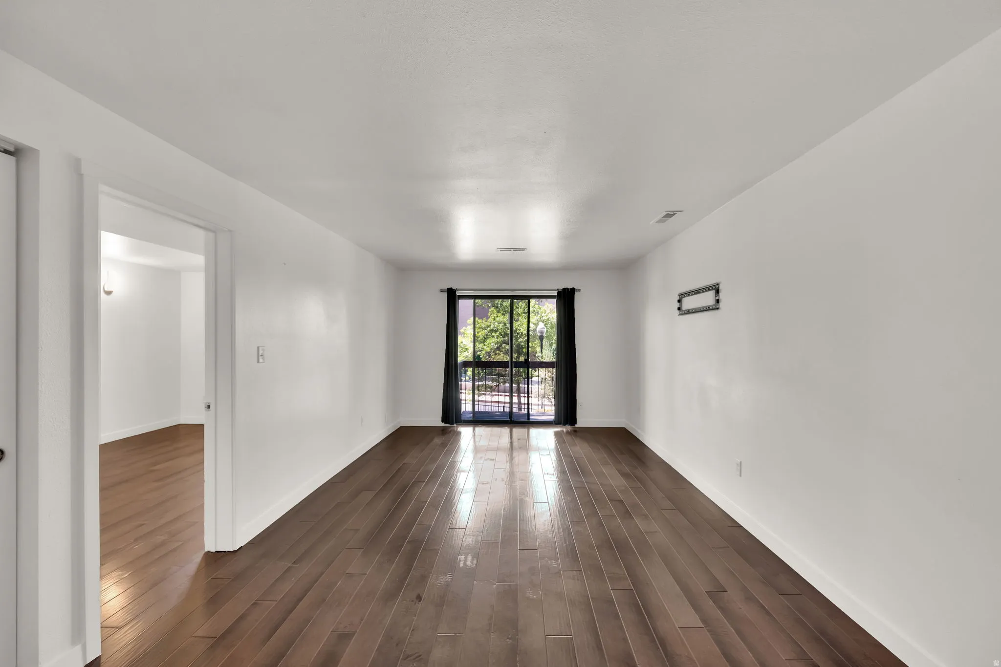 Spacious room featuring wood-finish flooring and white walls