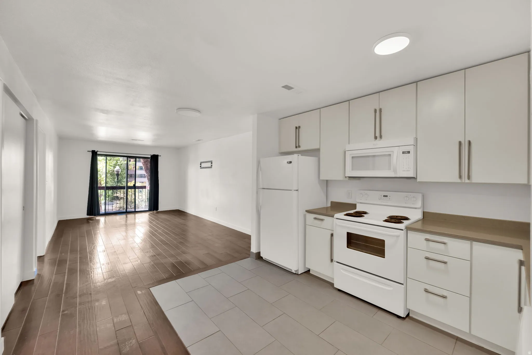 Kitchen featuring white cabinetry, integrated microwave, white electric range, and light-toned countertops