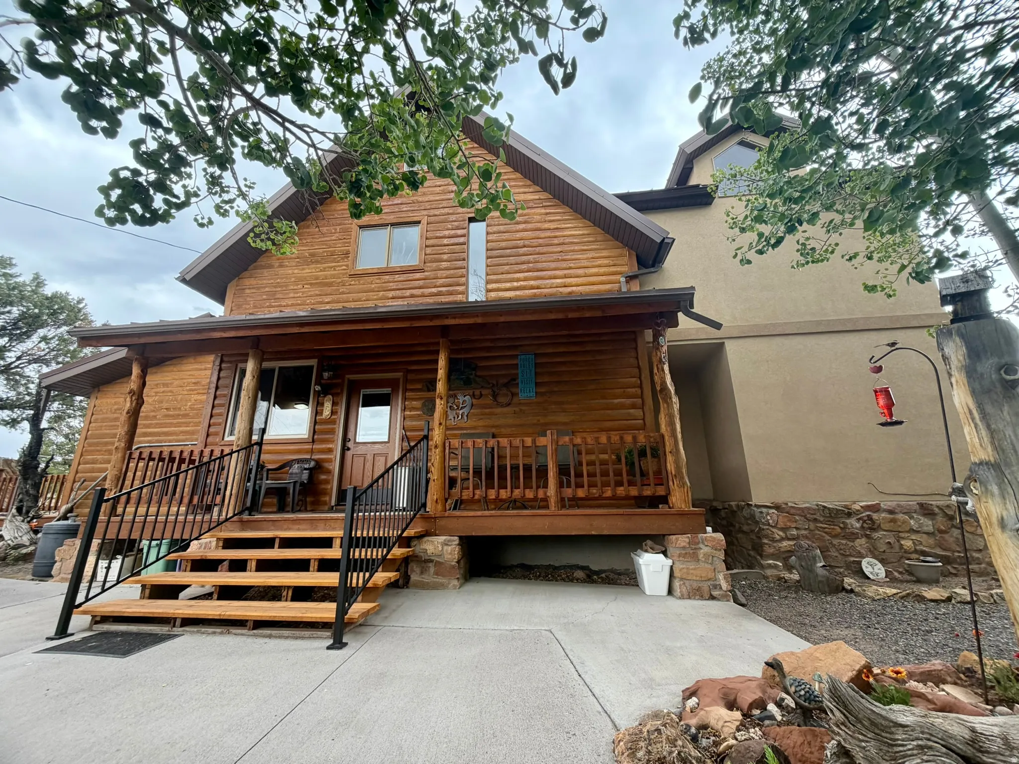 Log cabin exterior featuring a covered porch with wood railings and black metal balusters