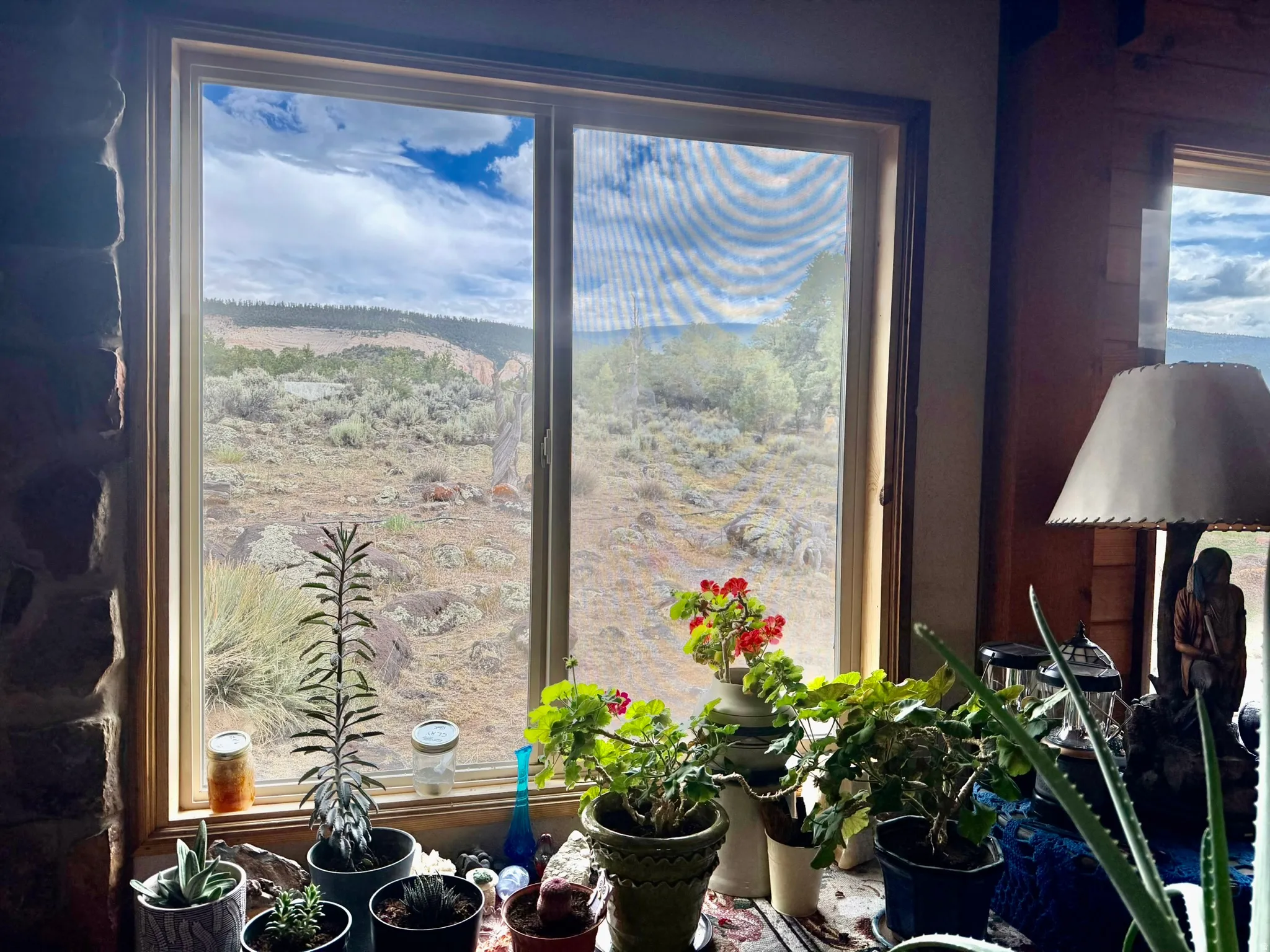 Expansive window framing a desert landscape with distant hills and a partially cloudy sky