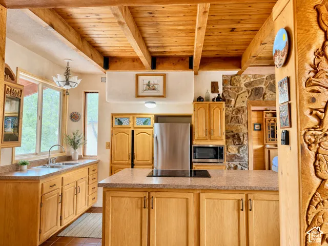 Kitchen featuring light wood cabinetry, stone-finish countertops, and a wood-beamed ceiling