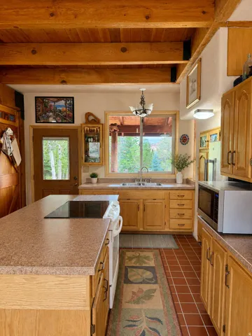 Kitchen featuring wood-finish cabinetry, solid surface countertops, and a central island with an integrated cooktop