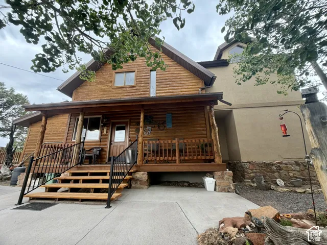 Log cabin exterior featuring a covered porch with wood railings and black metal balusters