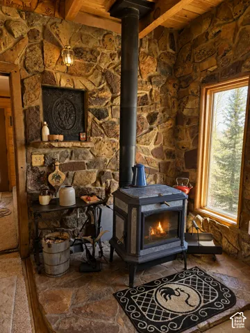 Stone accent wall with a built-in wood stove and exposed wood beam ceiling