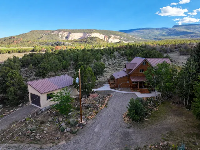 Wood-sided home with a multi-level roofline, surrounded by abundant natural landscaping