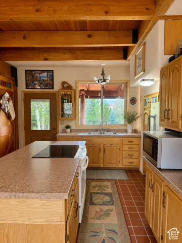 Kitchen featuring wood-finish cabinetry, solid surface countertops, and a central island with an integrated cooktop