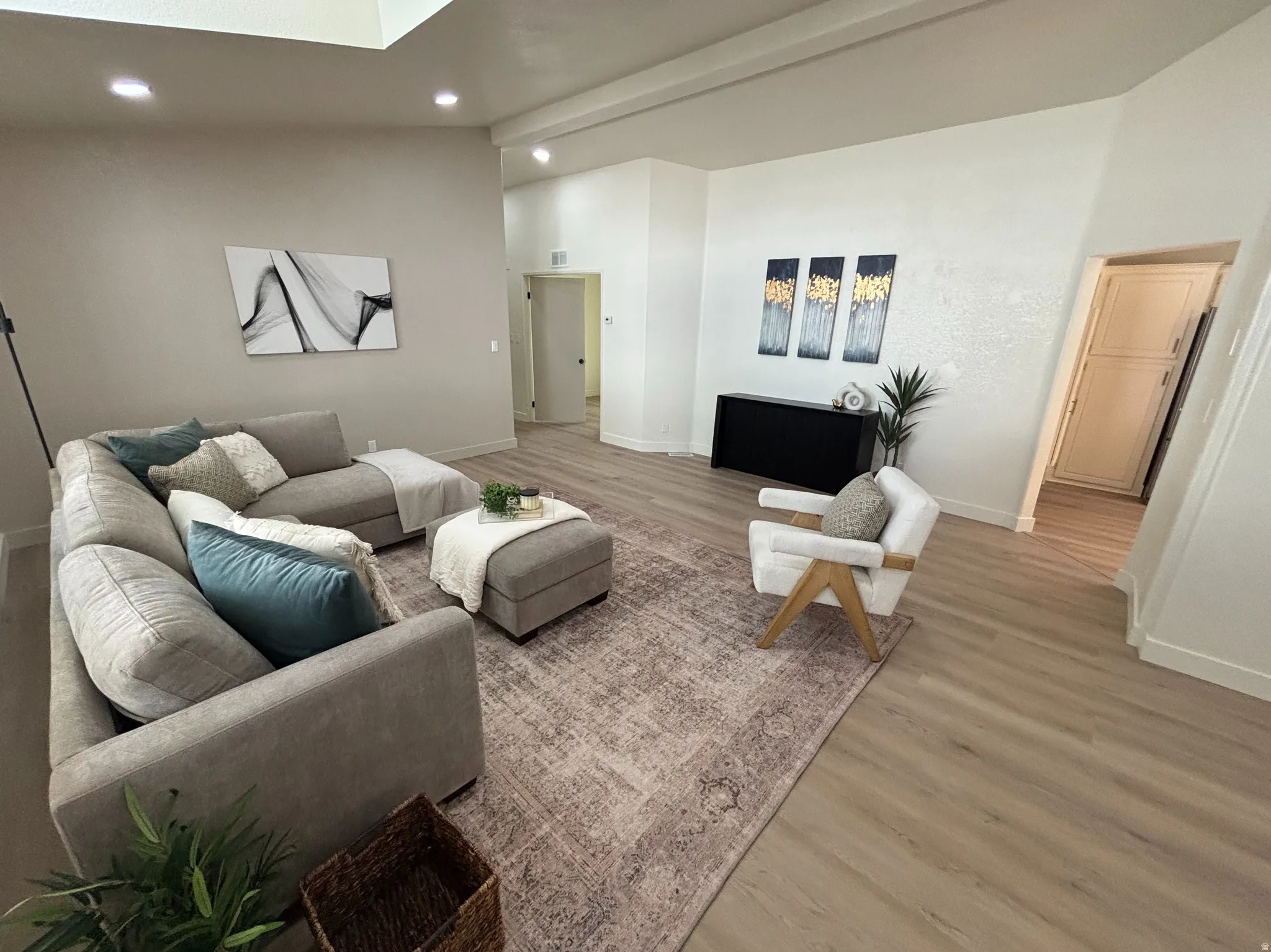 Spacious living area featuring wood-finish flooring and a central area rug