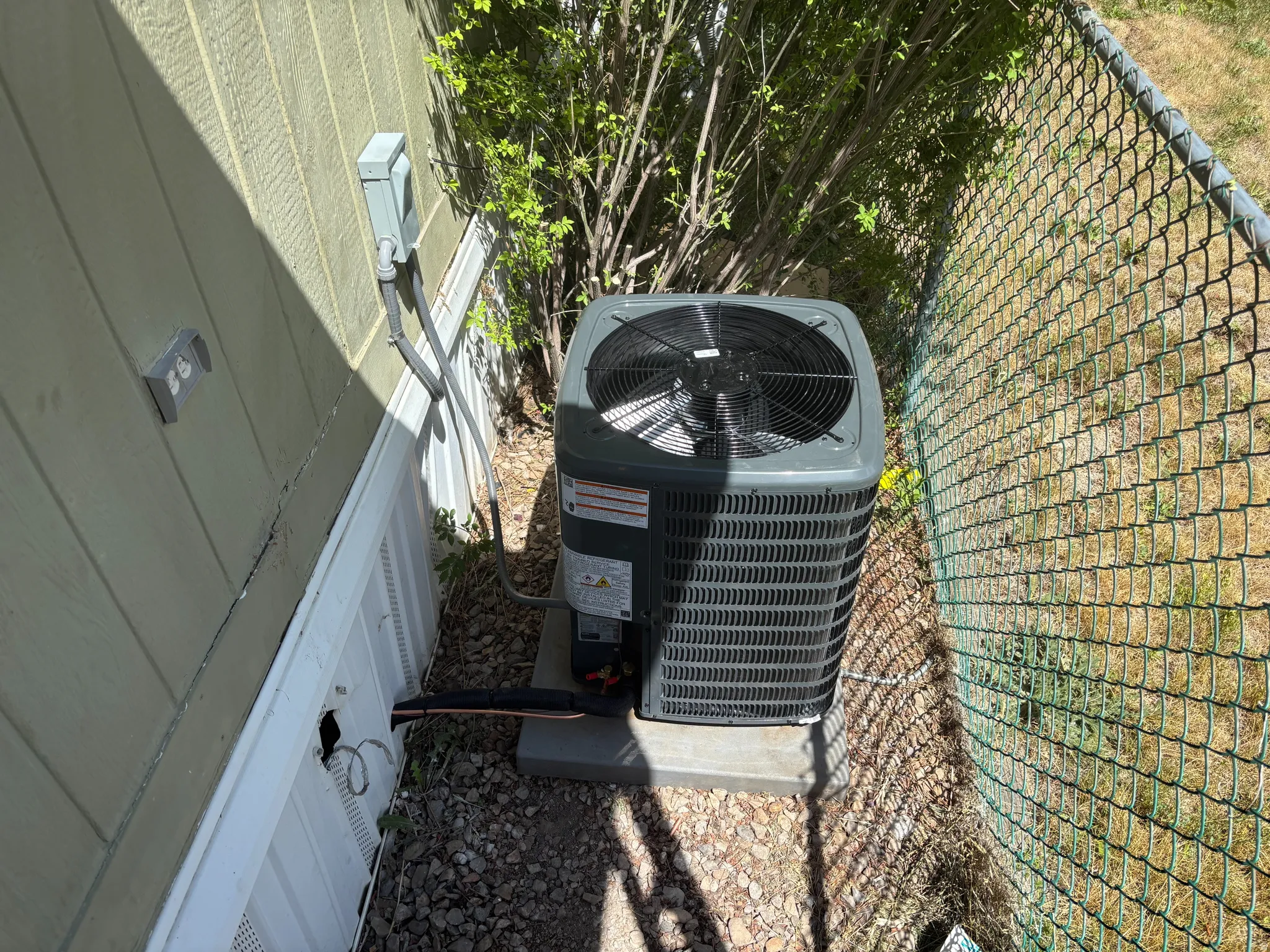 Exterior featuring horizontal siding, a chain-link fence, and a gravel ground cover