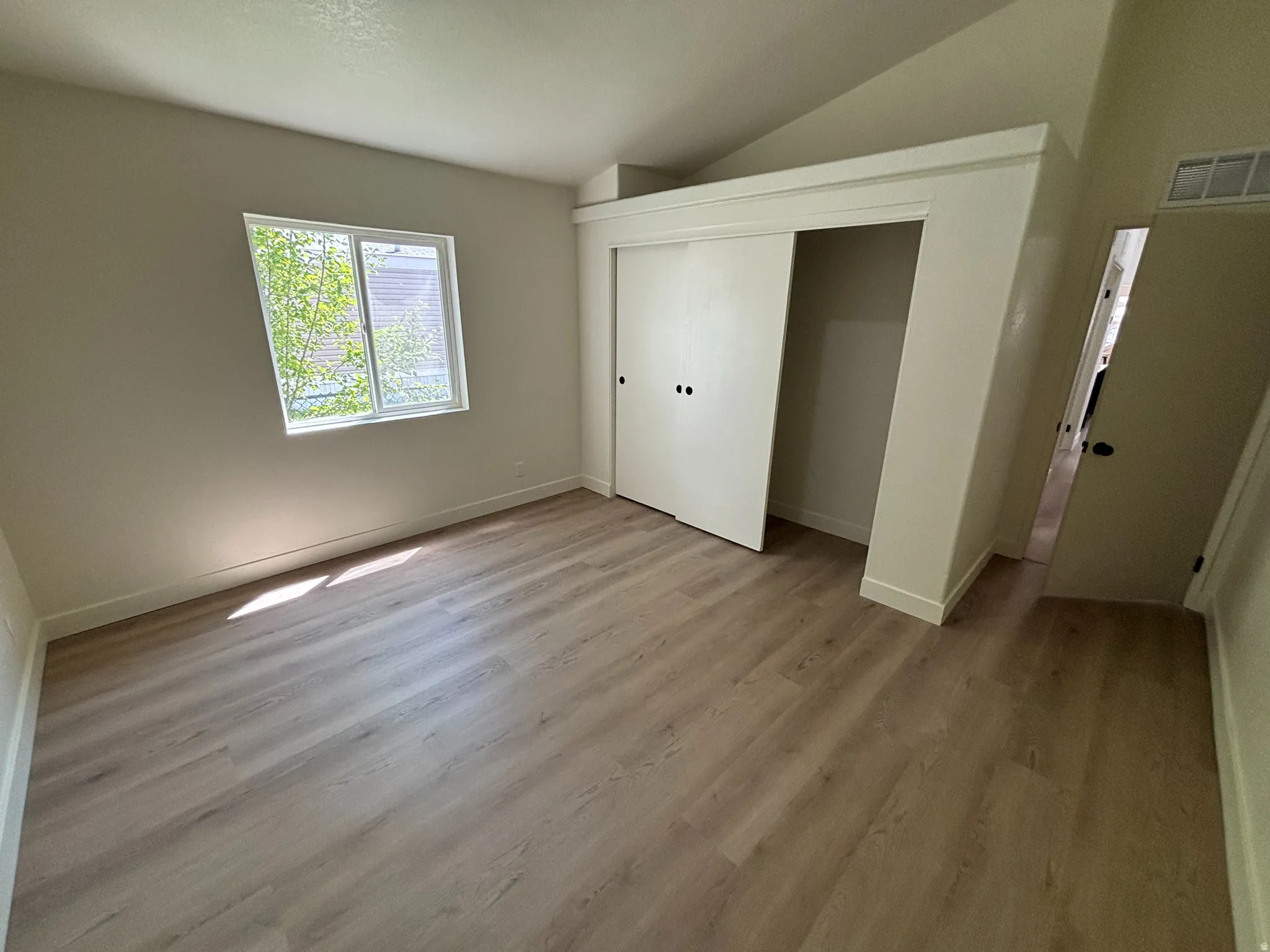 Room featuring wood-finish flooring, a bright window, and a built-in closet with sliding doors