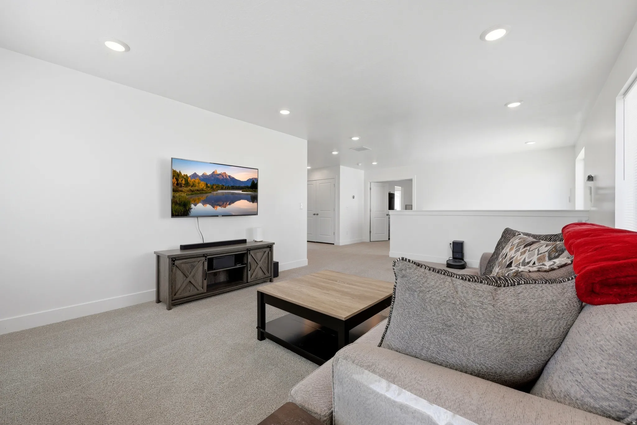 Recessed lighting illuminates neutral carpeting and white walls