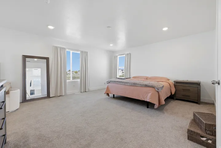 Spacious room featuring light-toned carpeting, white walls, and recessed lighting