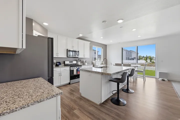 Contemporary kitchen featuring white cabinetry, stainless steel appliances, and granite countertops