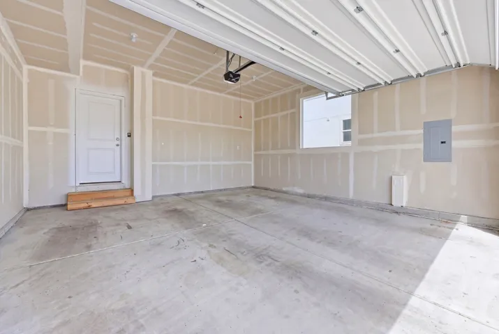 Spacious garage featuring a concrete floor, an overhead door, and an interior access door with wooden steps